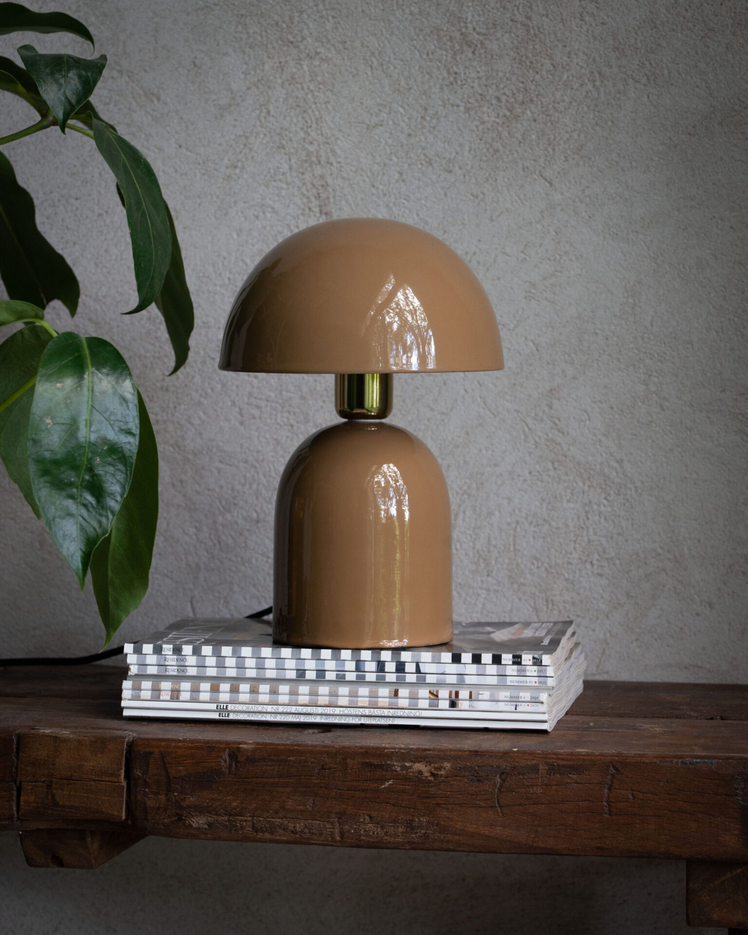Bordslampa Rome i brun från Wikholm ståendes på två böcker.
