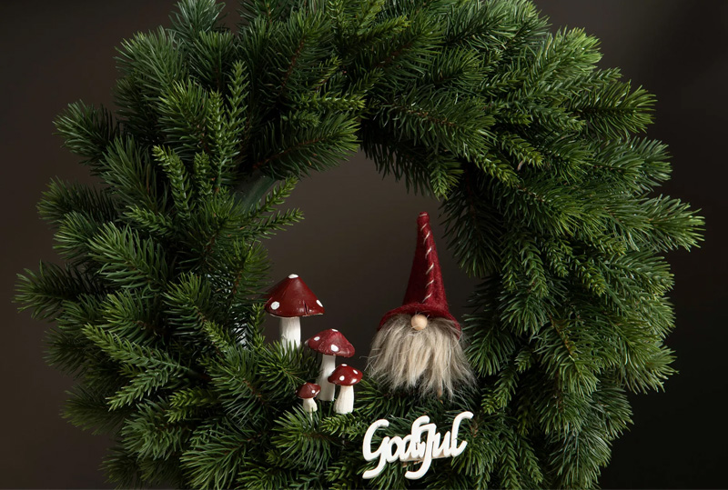 Grankrans med dekoration av tomtar och godjul-text.
