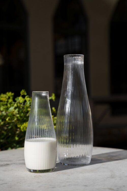 Karaff i räfflat glas i två storlekar från ERNST en fylld med mjölk.