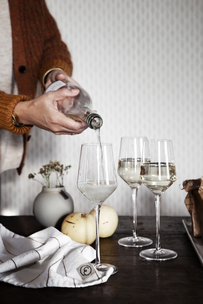Person som håller upp mousserande dryck i ERNST glas för mousserande.