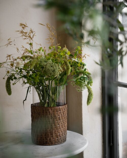 ERNST vas i flätad korg 30cm hög med gröna blomster i.